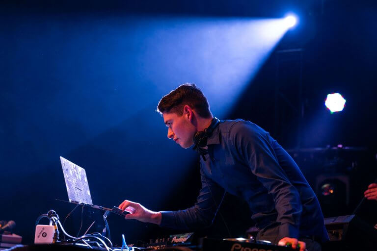 DJ Wayne am Mischpult unter blauem Bühnenlicht